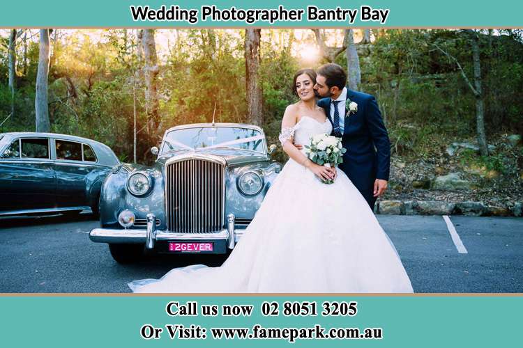 Photo of the Bride kiss by the Groom at the front of the bridal car Bantry Bay NSW 2087