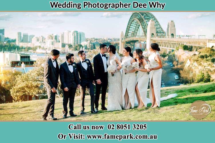 Photo of the Groom and the Bride kissing with the entourage under the bridge Dee Why NSW 2099