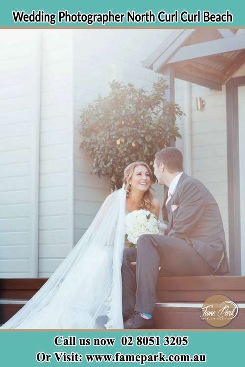 Photo of the Bride and the Groom looking each other sitting on the staircase North Curl Curl Beach NSW 2099